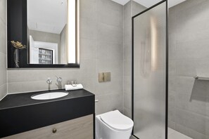 Ein modernes Badezimmer mit schwarzem Waschtisch, weißem Waschbecken und einer Duschkabine aus Glas.
