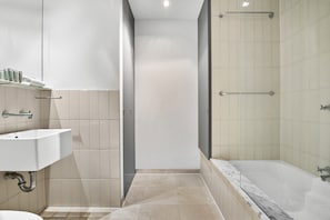 Ein modernes Badezimmer mit Waschbecken, Spiegel und Duschbereich.