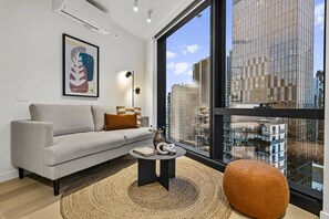 Ein modernes Wohnzimmer mit einer Couch, einem runden Couchtisch und einem großen Fenster mit Blick auf die Stadt.