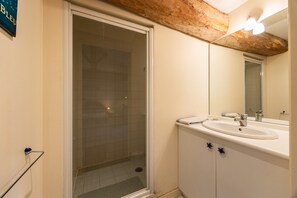 Un baño con cabina de ducha de vidrio, un lavabo y un espejo.