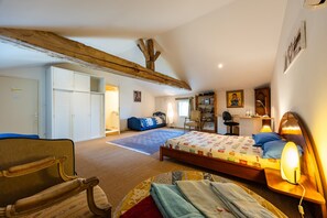 Un dormitorio con cama, escritorio, silla, armario y un amplio ventanal.