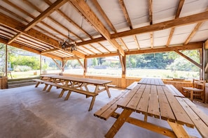 Un pabellón descubierto con vigas de madera y mesas de picnic.