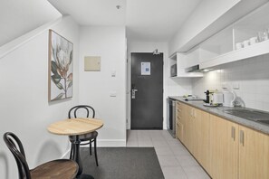 Et moderne køkken med spiseplads, en mørk dør og en hvid flisebeklædt bagvæg.