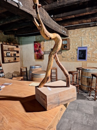 A rustic interior with wooden furniture, a wooden sculpture, and barrels.. Bed and Breakfast 'Chambre Merlot' with Shared Pool, Shared Terrace and Wi-Fi