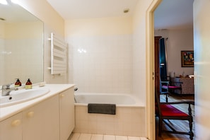 A bathroom with a bathtub, two sinks, and a towel rack.