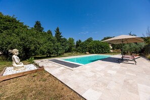Una piscina con una statua di Buddha, un'area patio coperta e vista su una zona boschiva.