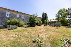 Un cortile con un edificio, posti a sedere all'aperto e vegetazione.
