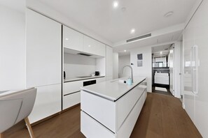 Una cocina moderna con armarios blancos, una isla central y suelo de madera.
