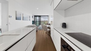 Eine moderne Küche mit weißen Schränken, einem Essbereich mit Tisch und Stühlen und Blick durch eine Glastür.