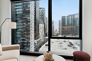 A modern room with a large window, a sofa, a lamp, and a decorative vase. - Southbank 2-Bed - Swepping City Views, Pool & Gym (Southbank)