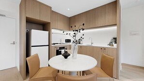 Une cuisine moderne avec des meubles en bois, un réfrigérateur blanc, une table à manger avec des chaises et un vase décoratif.