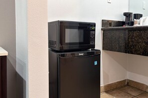 Una cocina compacta con microondas y refrigerador, una encimera con cafetera y piso de baldosas.