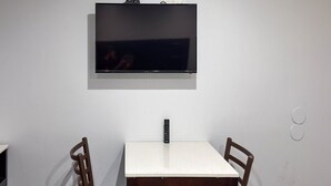 A dining area with a TV mounted on the wall, a table, and two chairs. - 2 Full Beds|Nsmk, Micfridge (Oakland)