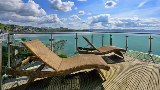 Terraza con sillones de mimbre que dan a un cuerpo de agua y un paisaje lejano.