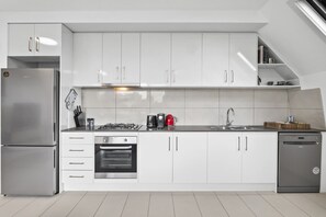Una cocina moderna con gabinetes blancos, electrodomésticos de acero inoxidable y un horno empotrado.