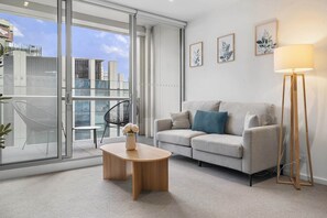 Una sala de estar moderna con un sofá, una mesa de centro, una lámpara de pie y vistas amplias a través de grandes ventanales.