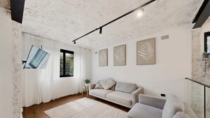 Een moderne woonkamer met een bank, een vloerkleed en kunstwerken in lijsten aan de muur.