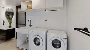 Een wasruimte met twee wasmachines, een wasbak en een spiegel.