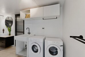 A laundry area with two washing machines, a sink, and a mirror. - Sunlit 3-Bed Coastal Stay with Private Deck (Cronulla)