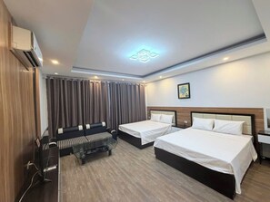 Una habitación de hotel con dos camas, un sofá, un escritorio y un equipo de aire acondicionado.