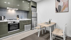 Una cocina moderna con electrodomésticos de acero inoxidable, un área de comedor con mesa y sillas, y una obra de arte colgada en la pared.
