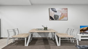 Un comedor con una mesa, sillas y un cuadro en la pared.