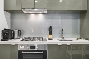 A modern kitchen with a Bosch range hood, a Philips coffee maker, a gas stove, and a dishwasher. - Elevated 1-Bed Retreat Near Crown (Southbank)