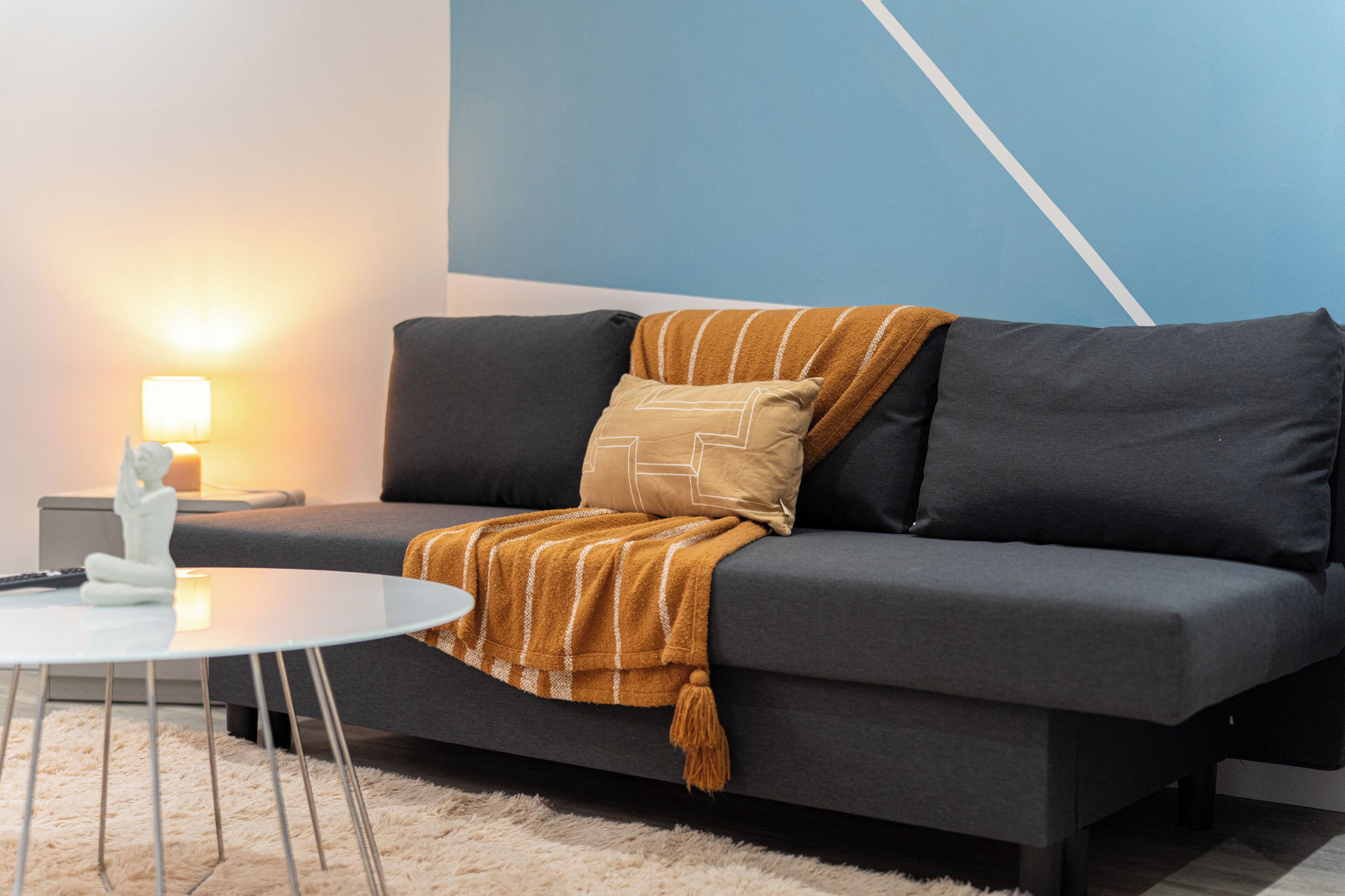 A modern living room with a grey sofa, a white coffee table, and a lamp on a side table.