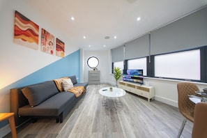 Ein modernes Wohnzimmer mit Sofa, Couchtisch und Fernseher.