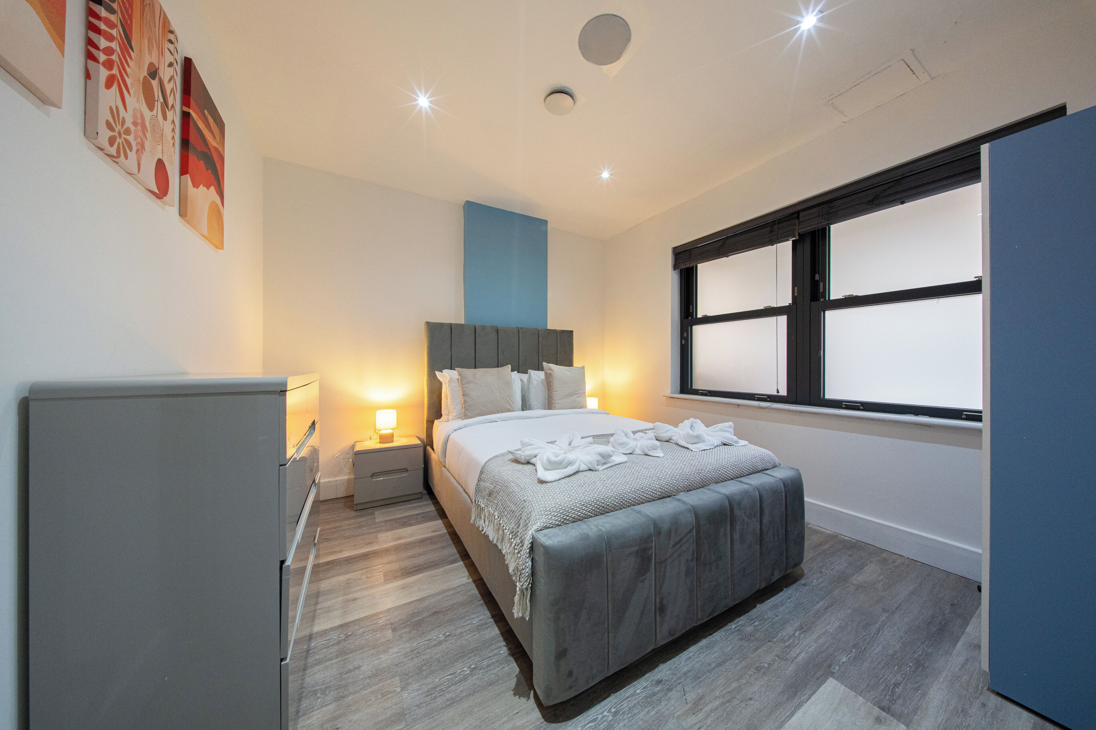 Een moderne slaapkamer met een bed, nachtkastjes, een kledingkast en een raam.