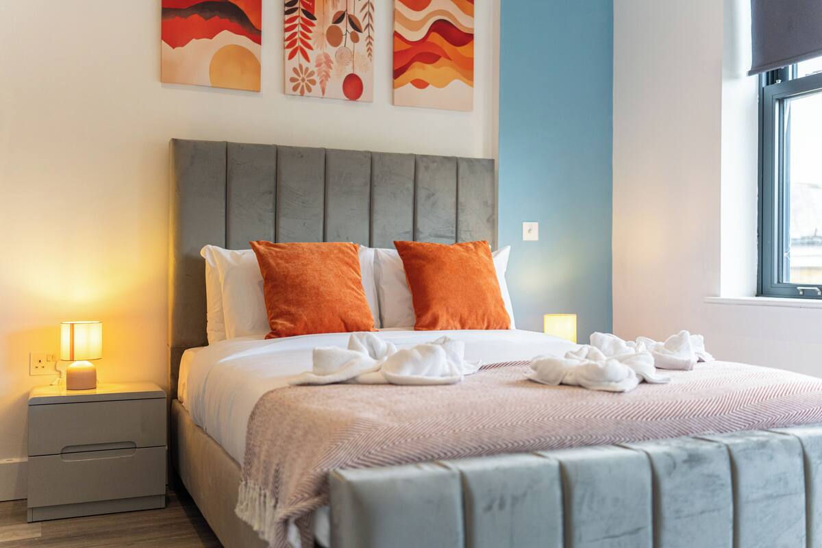 Uma cama bem arrumada com almofadas, um abajur e uma mesa de cabeceira.