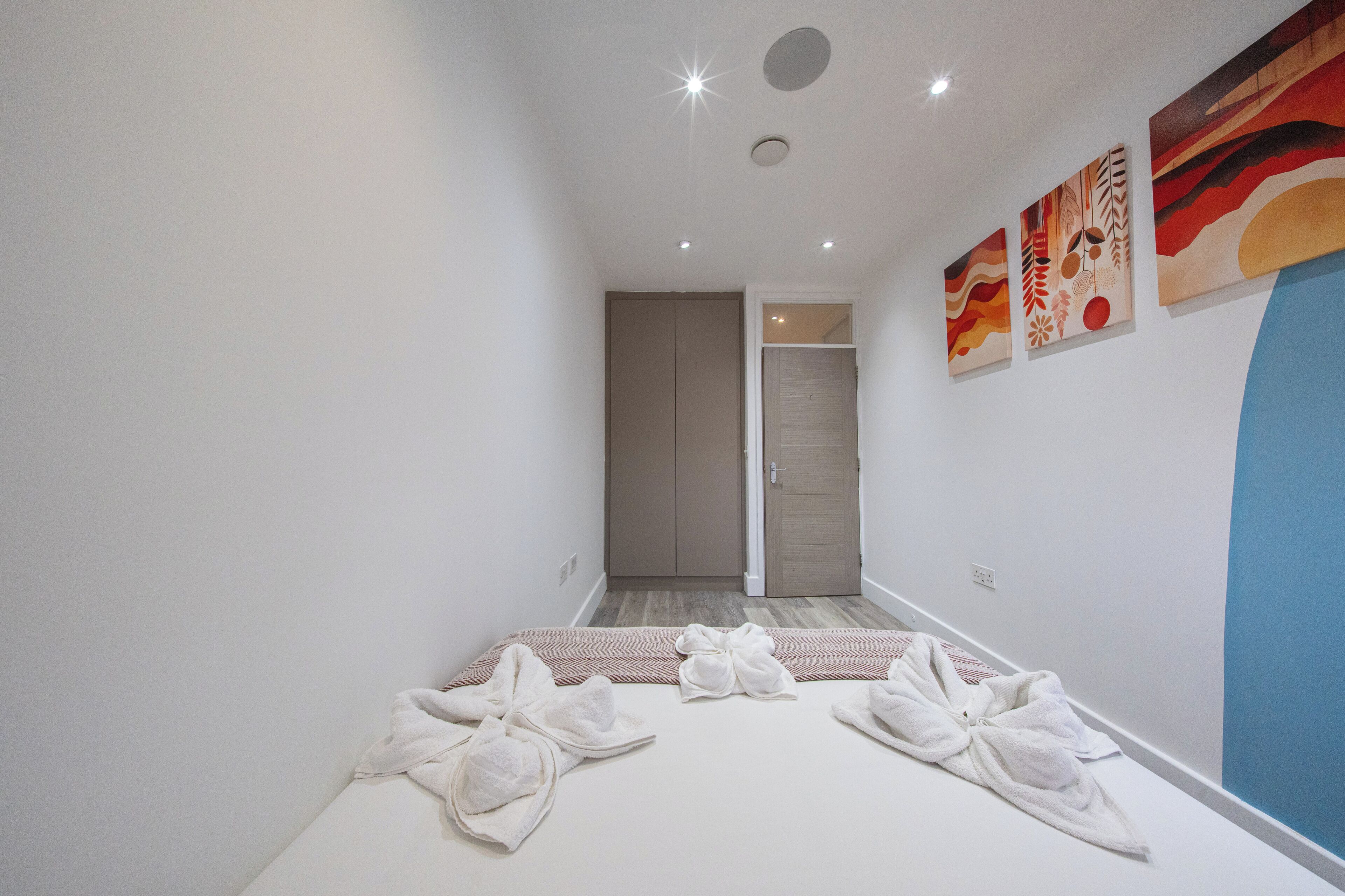 Une chambre d’hôtel avec un lit, des serviettes, une porte et des œuvres d’art mural.