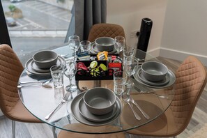 A dining table set for four with clear glassware, plates, and bowls. - Imperial Fulham Apartments (London)