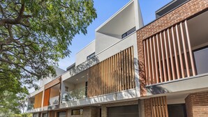 A modern building with a brick facade, large windows, and a covered outdoor area. - Stylish 3-Bed Townhouse Near City Fringe (Everard Park)