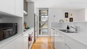 Een moderne keuken met witte kasten, roestvrijstalen apparatuur en een houten vloer.