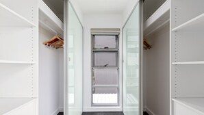 Een smalle inloopkast met open planken, een schuifdeur en een vloerbedekking.