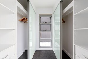 A narrow walk-in closet with open shelving, a sliding door, and a carpeted floor. - Spacious 2-Bed Retreat in Rosebery (Rosebery)