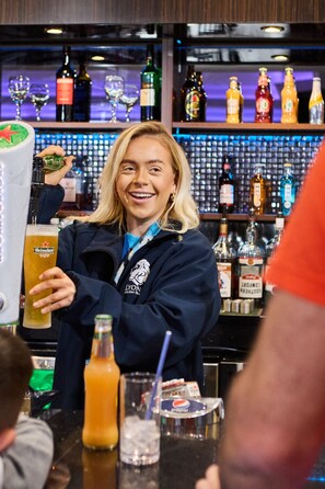 Ein Barkeeper hinter einer Bar mit einer Auswahl an Flaschen und Gläsern.