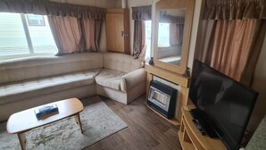 Un espace de vie compact comprenant un canapé, une petite table, un téléviseur et une cheminée.