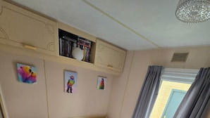 Une chambre avec deux lits, une étagère remplie de livres et une fenêtre avec des rideaux.