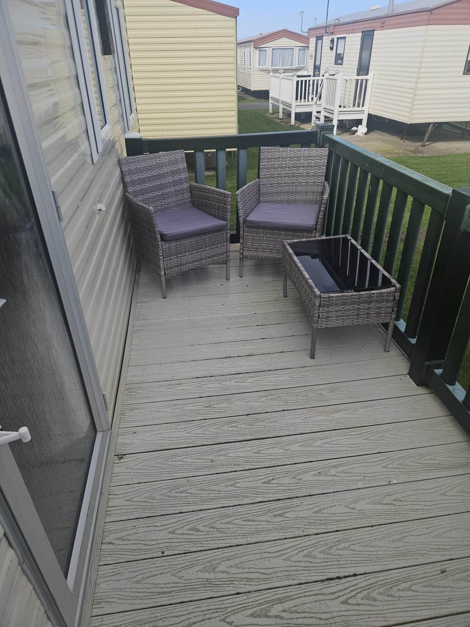 Eine Holzterrasse mit Korbmöbeln und einem kleinen Tisch.