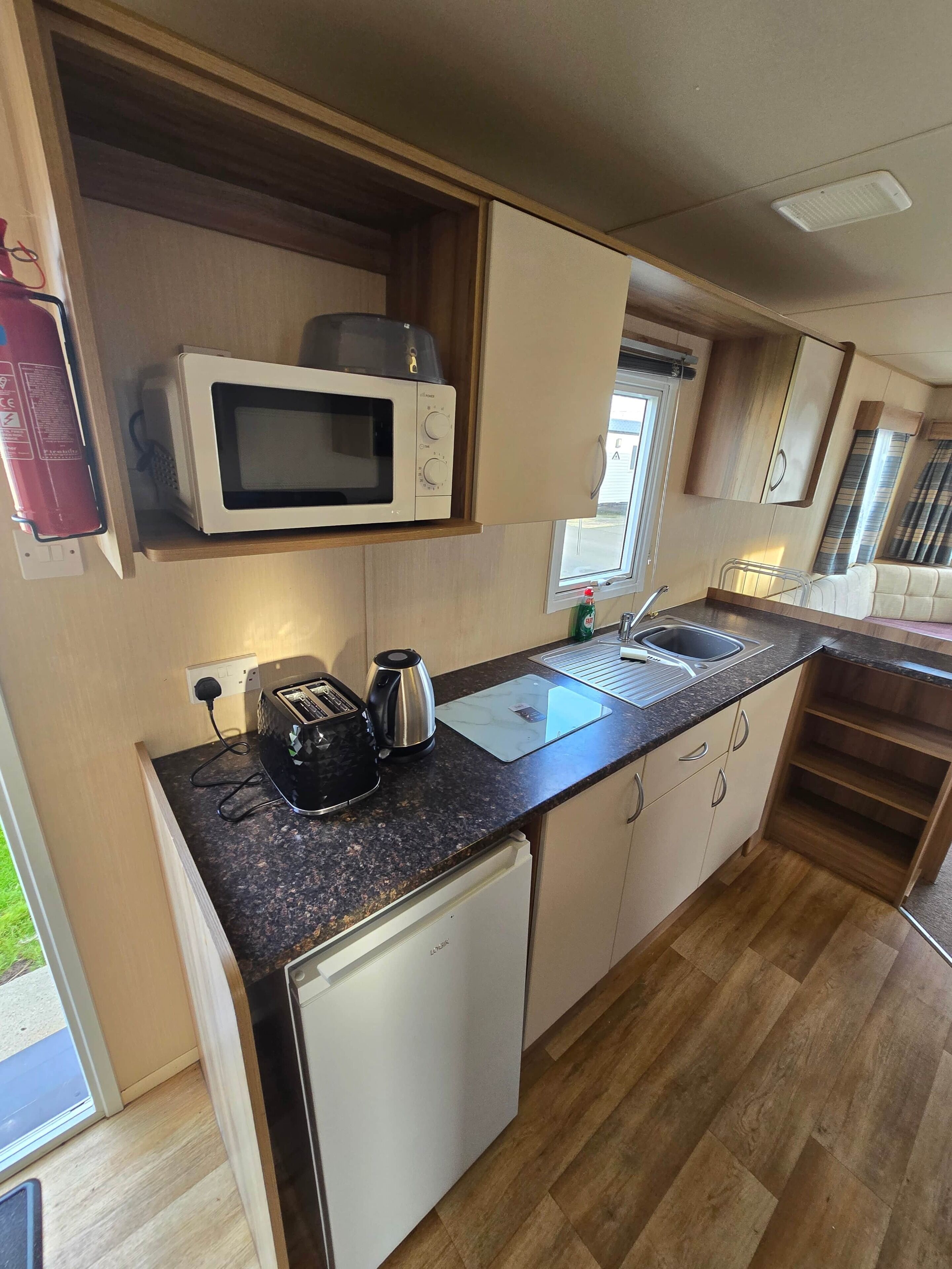 Una cocina compacta con microondas, tostadora, hervidor y un refrigerador pequeño.