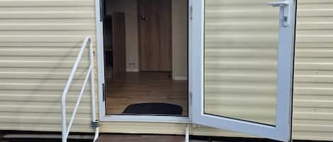A mobile home with an open door, a small set of steps leading inside, and a visible interior hallway.