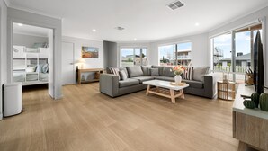 Un salón moderno con un sofá gris, una mesa de centro blanca y vistas al exterior.
