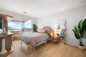 Quarto com cama, mesas de cabeceira, um espelho e um vaso de planta.