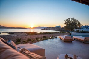 Sonnenuntergangblick von einer Terrasse mit Liegestühlen und einem Pool.