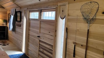 Een houten interieur met een grote deur, een blauwe mat en visgerei.