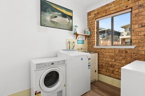A laundry room with a washing machine, dryer, and a window with a view of a building.