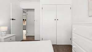 A hotel room with a bed, a nightstand with a lamp, a dresser, and a wardrobe. - Oceanview 3-Bedroom Apartment in Kiama (Kiama)