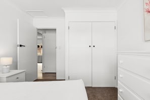 A hotel room with a bed, a nightstand with a lamp, a dresser, and a wardrobe. - Oceanview 3-Bedroom Apartment in Kiama (Kiama)